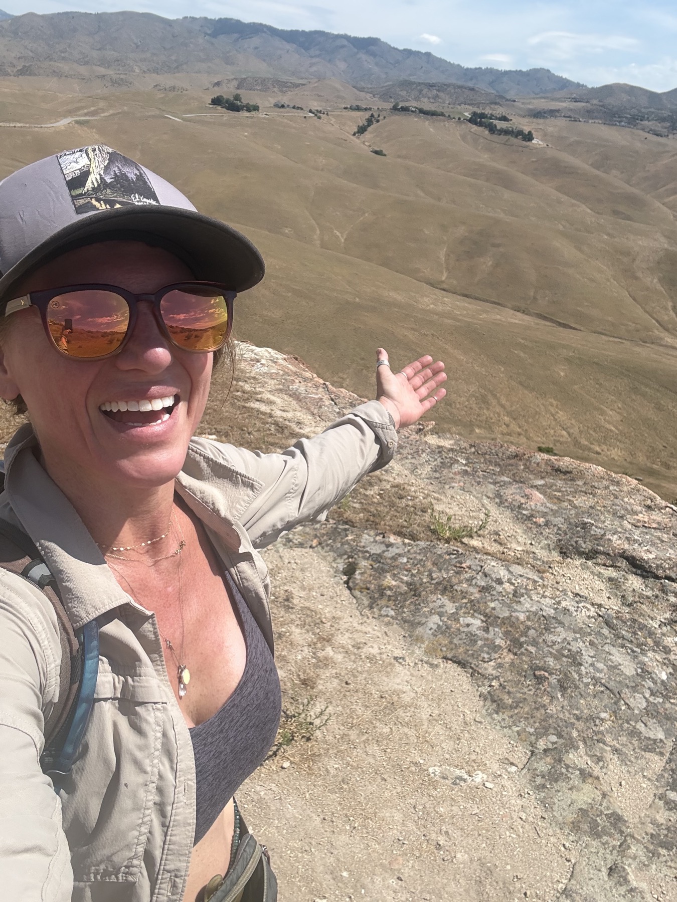 Chasta smiling on a mountain overlook with open hills behind her