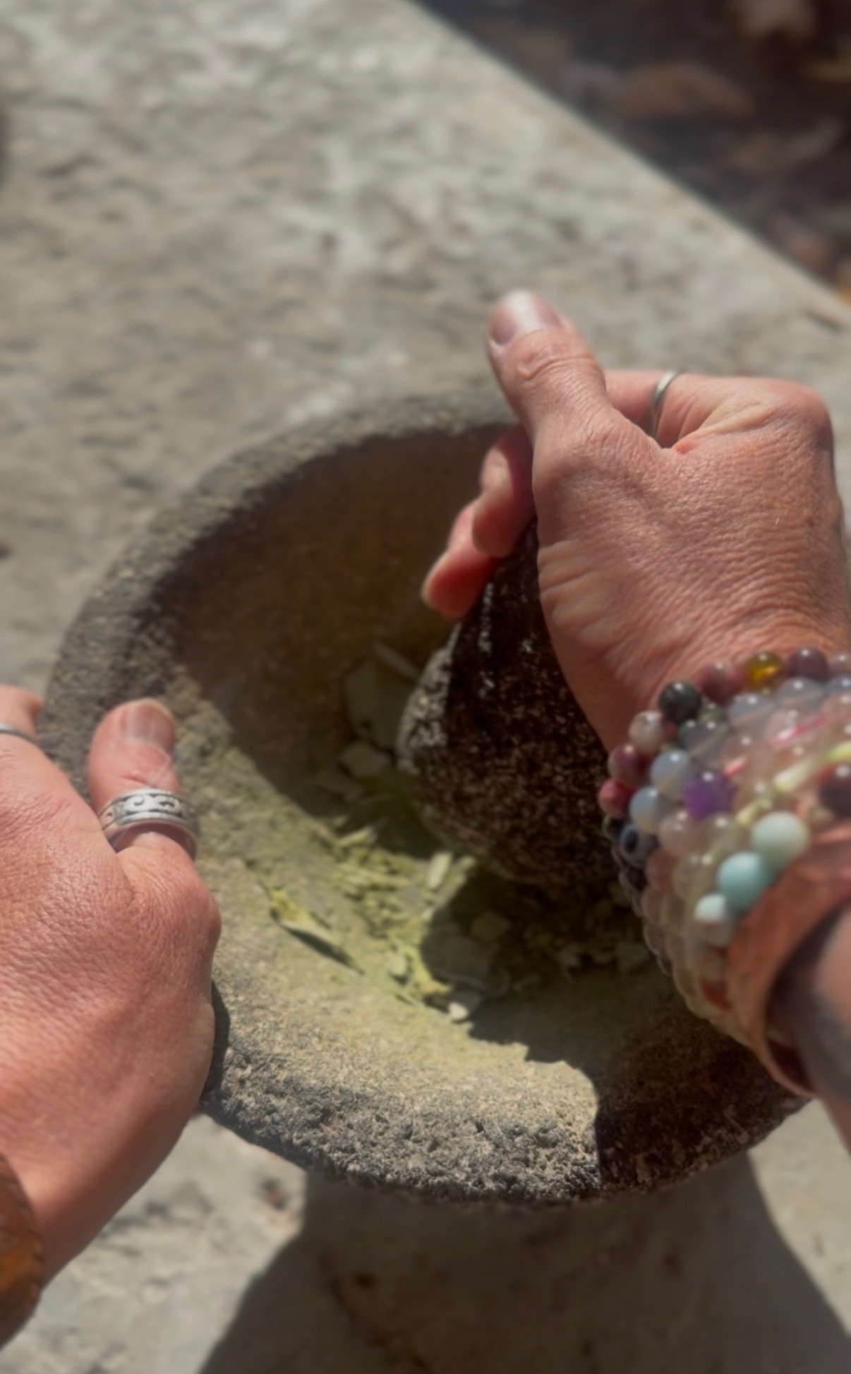 Chasta blending fresh botanicals by hand in a stone mortar and pestle