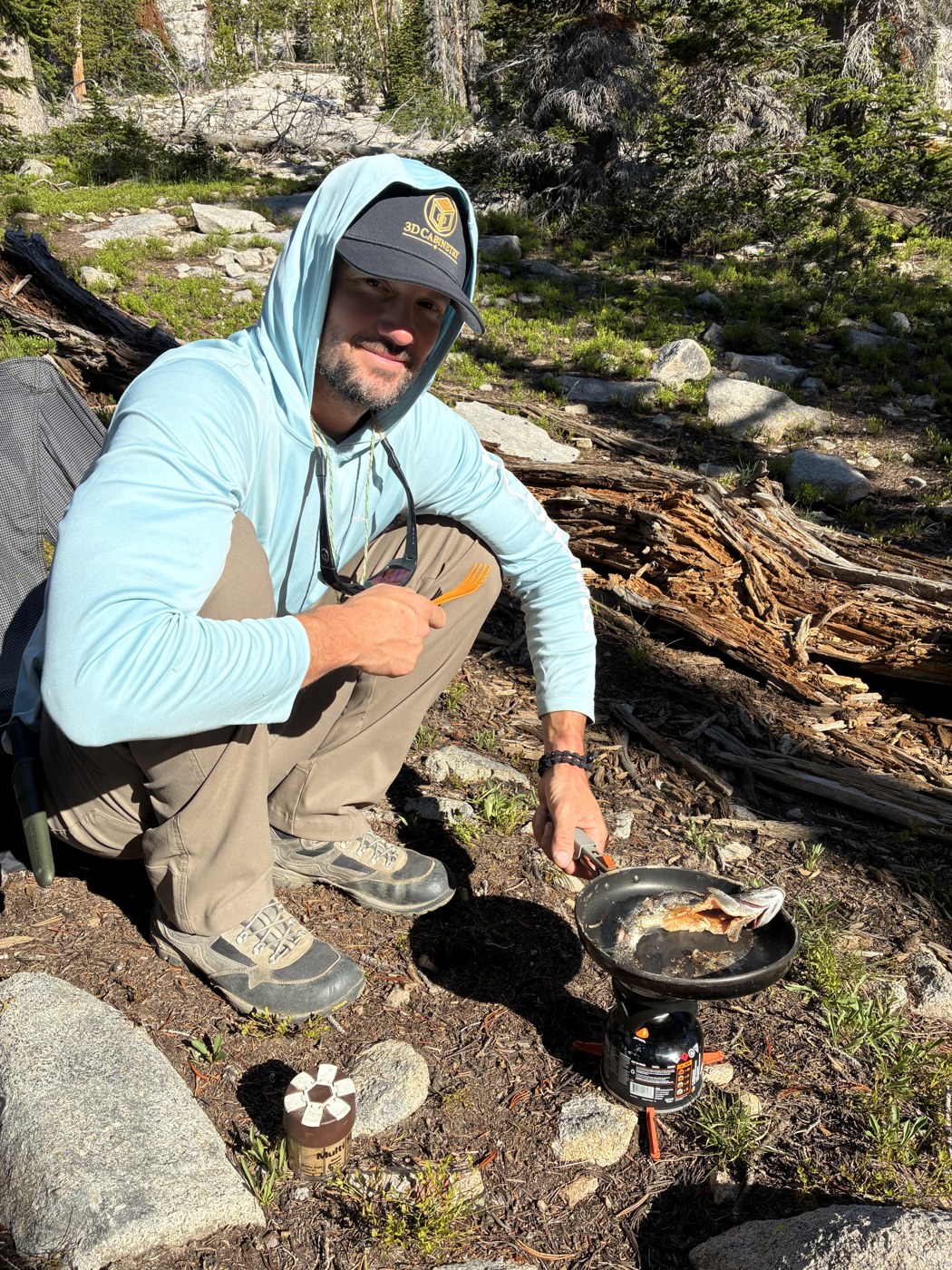 Jason Soubliere cooking a meal at a forest campsite